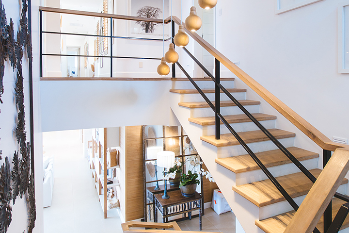 Wooden stairs leading up and down to the first and second floors of a home with white walls.