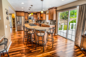 A kitchen with a large island in the middle, beautiful wooden floors and doors to a patio.